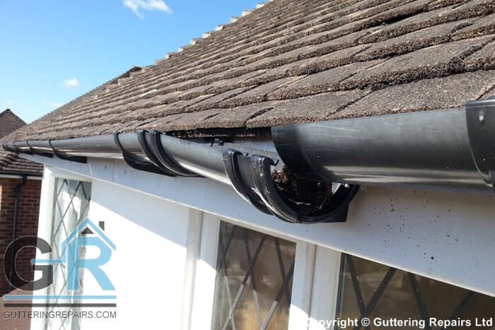 A roof in need of guttering repairs and minor roof repairs on a detached property in London.