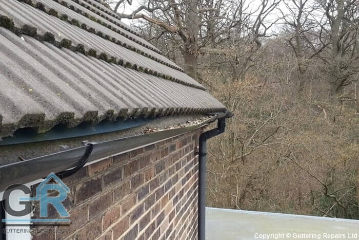 Sagging PVC roof gutter causing rainwater to overflow on a residential property.