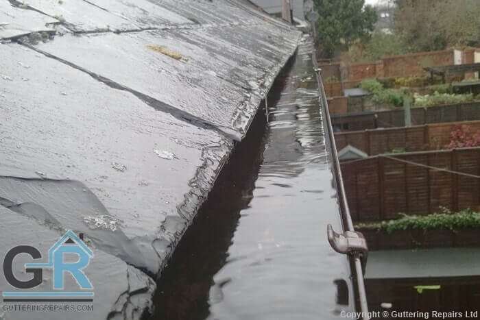 Overflowing rain gutter on a residential property due to a blockage in the downpipe.