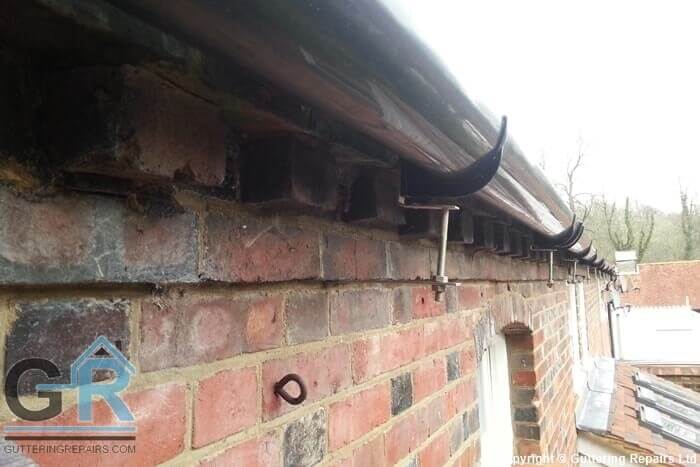 Traditional rise and fall gutter brackets supporting modern PVC roof gutters on a converted barn.